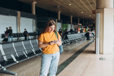 Happy Kafkasyalı Kadın, Uçuş Kapıları 'nda bekliyor. Uçağa binmek için, Mobil Akıllı Telefon kullanıyor. 30 'lu yaşlardaki kadın İnternet' te Yolculuk Hedefini Denetliyor, seyahat kavramı