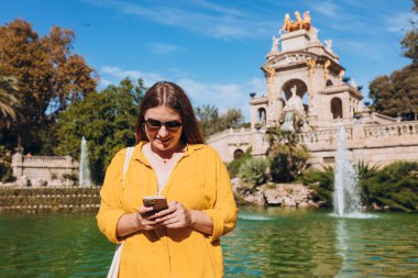 Barselona 'daki Ciutadella Parkı' na telefon eden genç bir turist. Seyahat, turizm ve tatil kavramı. Teknoloji kavramı kullan