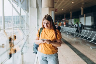 Happy Kafkasyalı Kadın, Uçuş Kapıları 'nda bekliyor. Uçağa binmek için, Mobil Akıllı Telefon kullanıyor. 30 'lu yaşlardaki kadın İnternet' te Yolculuk Hedefini Denetliyor, seyahat kavramı