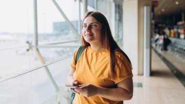 Happy Kafkasyalı Kadın, Uçuş Kapıları 'nda bekliyor. Uçağa binmek için, Mobil Akıllı Telefon kullanıyor. 30 'lu yaşlardaki kadın İnternet' te Yolculuk Hedefini Denetliyor, seyahat kavramı