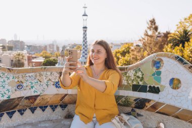 Gaudi Bahçesi, İspanya, Barselona 'da güzel bir kadın. Genç gezgin kadın dışarıda selfie çekiyor. Seyahat, turizm ve tatil kavramı