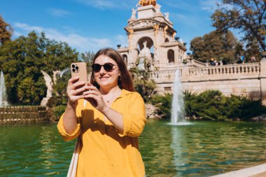 Genç bayan turist Barselona 'daki Ciutadella Parkı' nı ziyaret ediyor. Genç gezgin kadın dışarıda selfie çekiyor. Seyahat, turizm ve tatil kavramı