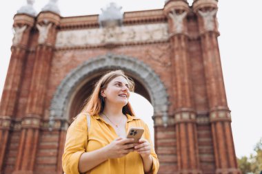 Yaz tatilinde telefonu akıllı bir kadın Barcelona kemerinin yanında duruyor. Seyahat, turizm ve tatil pankartları. Teknoloji kavramını kullan, Avrupa 'yı gezmek