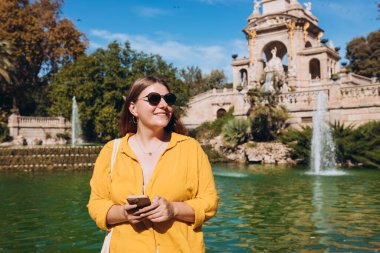 Barselona 'daki Ciutadella Parkı' na telefon eden genç bir turist. Seyahat, turizm ve tatil kavramı. Teknoloji kavramı kullan
