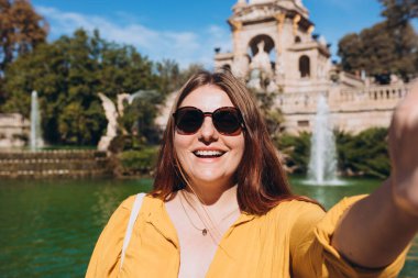 Genç bayan turist Barselona 'daki Ciutadella Parkı' nı ziyaret ediyor. Genç gezgin kadın dışarıda selfie çekiyor. Seyahat, turizm ve tatil kavramı. Teknoloji kavramı kullan