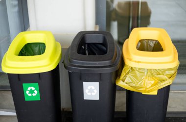 Çöpleri ayırmak için renkli çöp kutuları. Plastik, cam, kağıt ve diğer atıklar için. Polonya 'da bir duvarın yanında duran atık konteynırları..