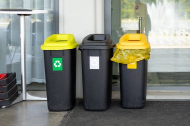 Çöpleri ayırmak için renkli çöp kutuları. Plastik, cam, kağıt ve diğer atıklar için. Polonya 'da bir duvarın yanında duran atık konteynırları..