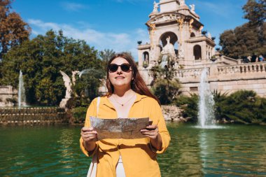 Barselona 'daki Ciutadella Parkı' nı ziyaret eden kağıt haritalı genç bir bayan turist. Seyahat, turizm ve tatil kavramı