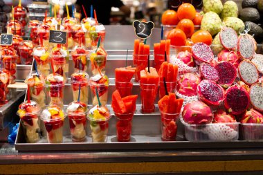 Markette plastik bardaklara yerleştirilmiş meyve salatası. Piyasada satılmaya hazır meyveler. Uygun, sağlıklı bir yaşam tarzı. Çilek, kivi, karpuz, avokado, ejderha meyvesi.