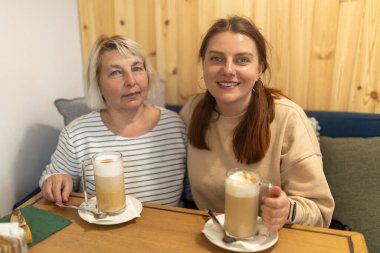 Mutlu grup gülümsemesi kapalı bir restoranda bir fincan kahveyle eğlenceli sohbetin keyfini çıkarıyor.
