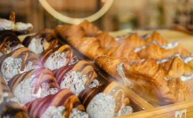 Pastanenin vitrininde çeşitli taze hamur işleri var. Rafta satılık ayçöreği var.