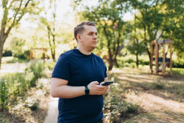 Sokakta akıllı telefon kullanan 30 'lu yaşlarda kendine güvenen bir adam. İletişim ve cihazlar, bağlantı konsepti. Dışarıda dinlenirken cep telefonu tutan bir adam.