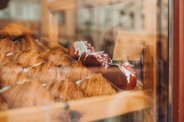 Pastanenin vitrininde çeşitli taze hamur işleri var. Rafta satılık ayçöreği var.