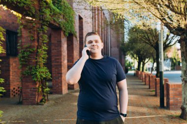 Şehir caddesinde akıllı telefondan konuşan 30 'lu yaşlardaki mutlu sarışın adam. İletişim ve aygıtlar, bağlantı kavramı