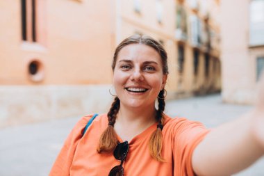 Fotoğraf rahatlatıcı pozitif kadın kamerayı tut ve dışarıda şehir merkezinde selfie çek. Yaşam tarzı turist seyahati konsepti.