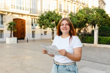 Çekici bayan turist yeni şehri keşfediyor. Kızıl saçlı kadın İspanya ya da İtalya 'da elinde bir harita tutuyor. Avrupa 'yı gezmek