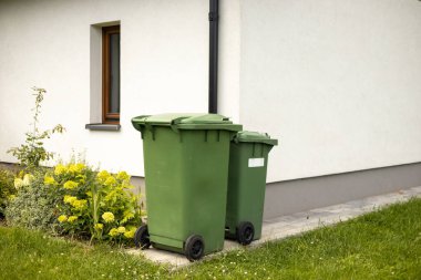 Modern evin önünde iki tane boş yeşil plastik çöp kutusu. Plastik kirliliği sorunu.