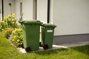 Modern evin önünde iki tane boş yeşil plastik çöp kutusu. Plastik kirliliği sorunu.