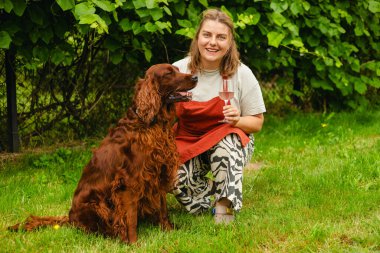 30 'ların önlüklü kadını, köpeğiyle üzüm bağında pembe şarap tadıyor. Elinde şarap kadehi olan güzel bir genç kadının portresi. Happy Vintner başarılı üzüm hasadından sonra şarap içer. Hasat zamanı