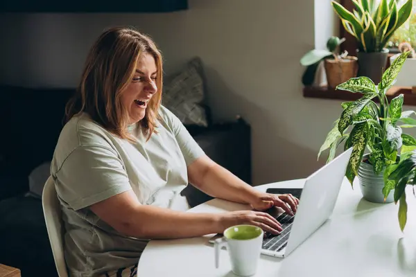 stock image Tired businesswoman yawning at her desk while working on a laptop. Female freelancer works in home office workplace. A woman is sleeping on her laptop at her desk.