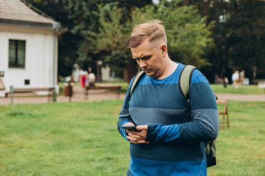 Üzgün genç bir adam dışarıda telefonla kötü haberler alıyor. 30 'lu yaşlarda bir adam parkta akıllı telefon kullanıyor. Negatif insanların duyguları