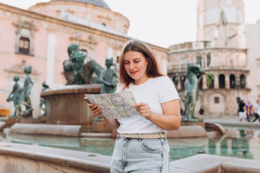 Çekici bayan turist yeni şehri keşfediyor. Kızıl saçlı kadın, Valencia Katedrali 'nin Bakire Meryem Meydanı' nda Rio Turia Çeşmesi yakınlarında kağıt bir harita tutuyor. Avrupa 'yı gezmek