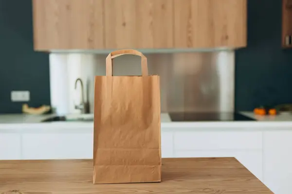 stock image Food craft bag on the wooden table in the kitchen. Delivery in any weather around the clock to the client. Fast food eco packaging with big breakfast