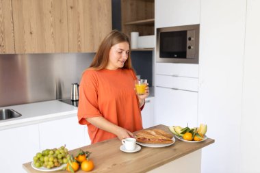 Mutfakta elinde bir bardak portakal suyu tutan mutlu 30 'lu yaşlarda bir kadın. Ev hayatı ve boş zaman anları. Yüksek kalite fotoğraf.