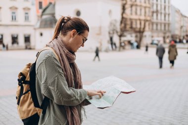 Çekici genç bayan turist yeni şehri keşfediyor. Krakow 'daki Pazar Meydanı' nda elinde kağıt harita tutan mutlu kız. Sonbaharda Avrupa 'yı gezmek