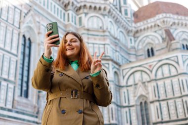 Floransa 'daki ünlü Duomo katedralinin yakınında akıllı telefon kullanan 30' lu yaşlardaki bir kız. Şehir tarihi geçmişinde selfie çeken mutlu kadın. Teknoloji kavramını kullan, Avrupa 'da Seyahat Sancağını