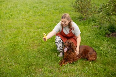 Neşeli, mutlu genç bir kadın yazın evin bahçesinde köpeğiyle oynuyor..