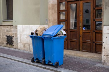 Yol kenarlarında kağıt olan mavi çöpler. Çöp toplama için yol kenarındaki plastik çöp bidonları.