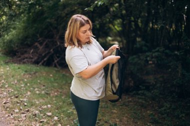 30 'lu yaşlardaki genç bir kadın doğanın güzelliği içinde sandalyesini hazırlıyor. Kamp, turizm ve seyahat konsepti. Mutlu sarışın bir kadın ormanı keşfediyor..