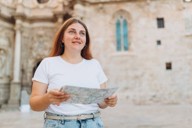 Çekici bayan turist yeni şehri keşfediyor. Kızıl saçlı kadın Bakire Meryem 'in yanında kağıt bir harita tutuyor, Valencia Katedrali.