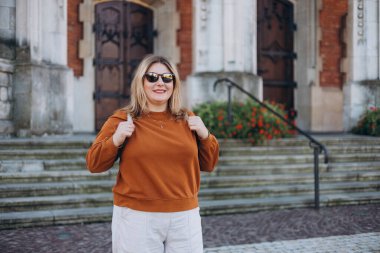 Tatil sırasında şehirde yürüyen mutlu turist kız. 30 'lu yaşlarda güneş gözlüklü neşeli bir kadın yazın yurt dışına seyahat ediyor. Seyahat ve aktif yaşam tarzı kavramı