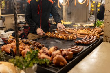 Polonya 'da bir ortaçağ fuarında sokak pazarında ızgara sosis. Sosis ve domuz eti yenmeye hazır. Sokak yemeği ve eti festivali. Noel Fuarı 'nda geleneksel sıcak yemek satmak..