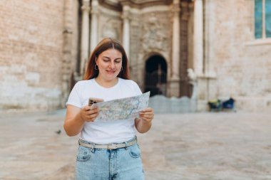 Çekici bayan turist yeni şehri keşfediyor. Kızıl saçlı kadın Bakire Meryem 'in yanında kağıt bir harita tutuyor, Valencia Katedrali.