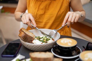 Kafede Shakshuka yiyen bir kadın. Geleneksel Orta Doğu yemeği. Domatesli yumurta ve bir fincan kahve. Kolay kahvaltı kavramı.