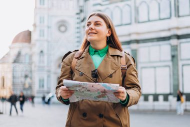 Floransa 'nın eski kasabasında haritası olan mutlu 30' lu yaşlarda genç bir kadın. Tatiller ve turizm konsepti. Sonbaharda yurtdışına seyahat ederken haritada yön arayan kadın turist
