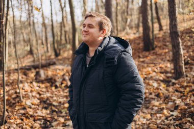 30 'lu yaşlarda erkek, macerada gülümsüyor. Yürüyüş, yaşam tarzı, macera ve turizm konsepti. Ormanda duran genç adam, sonbahar zamanı.