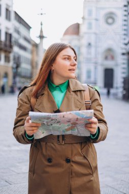 Floransa 'nın eski kasabasında haritası olan mutlu 30' lu yaşlarda genç bir kadın. Tatiller ve turizm konsepti. Sonbaharda yurtdışına seyahat ederken haritada yön arayan kadın turist