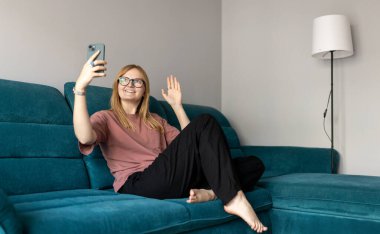 - Selam. Kadın evde cep telefonuyla selfie çekiyormuş. 30 'lu yaşlarda, tişörtlü bir kadın kendi videosunu çekiyor. İnternetten konuşuyor ve kanepede dinleniyor..