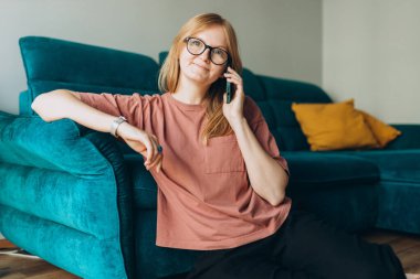 İletişim teknolojisi üzerine konuşan mutlu kadın. Evdeki kanepenin yanında konuşma, tartışma ya da sohbet, telefon görüşmesinde mutlu ve sosyal medya.