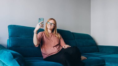 Genç bayan blogger cep telefonuyla video kaydediyor ya da canlı yayın yapıyor. Abone kitlesi, teknoloji ve yaşam tarzı afişi için özçekim hazırlayan içerik yaratıcısı