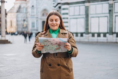 Floransa 'nın eski kasabasında haritası olan mutlu 30' lu yaşlarda genç bir kadın. Tatiller ve turizm konsepti. Sonbaharda yurtdışına seyahat ederken haritada yön arayan kadın turist
