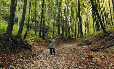 30 'lu yılların kadınları fotoğraf çekmek için telefon kullanır, özçekim yapar ve doğada arkadaşlarıyla görüntülü konuşmalar yapar. Seyahat ve seyahat tutkusu konsepti. İnanılmaz soğuk bir an.