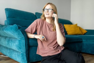 İletişim teknolojisi üzerine konuşan mutlu kadın. Evdeki kanepenin yanında konuşma, tartışma ya da sohbet, telefon görüşmesinde mutlu ve sosyal medya.