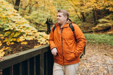 30 'lu yaşlarda erkek, macerada gülümsüyor. Yürüyüş, yaşam tarzı, macera ve turizm konsepti. Ormanda duran genç adam, sonbahar zamanı.
