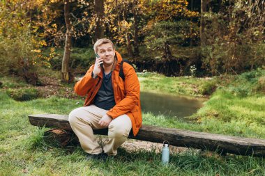 Dağ yolunda dinlenen ve telefonda konuşan yakışıklı genç adam. Özgürlük ve aktif yaşam tarzı kavramı. Yüksek kalite fotoğraf.