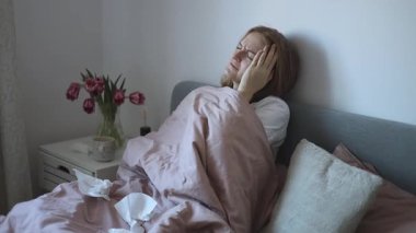 Hasta genç kadın yatakta öksürüyor. Genç bayan hapşırıyor ve yatakta dinleniyor. Kadın grip ya da soğuk algınlığı. Gerçek zaman